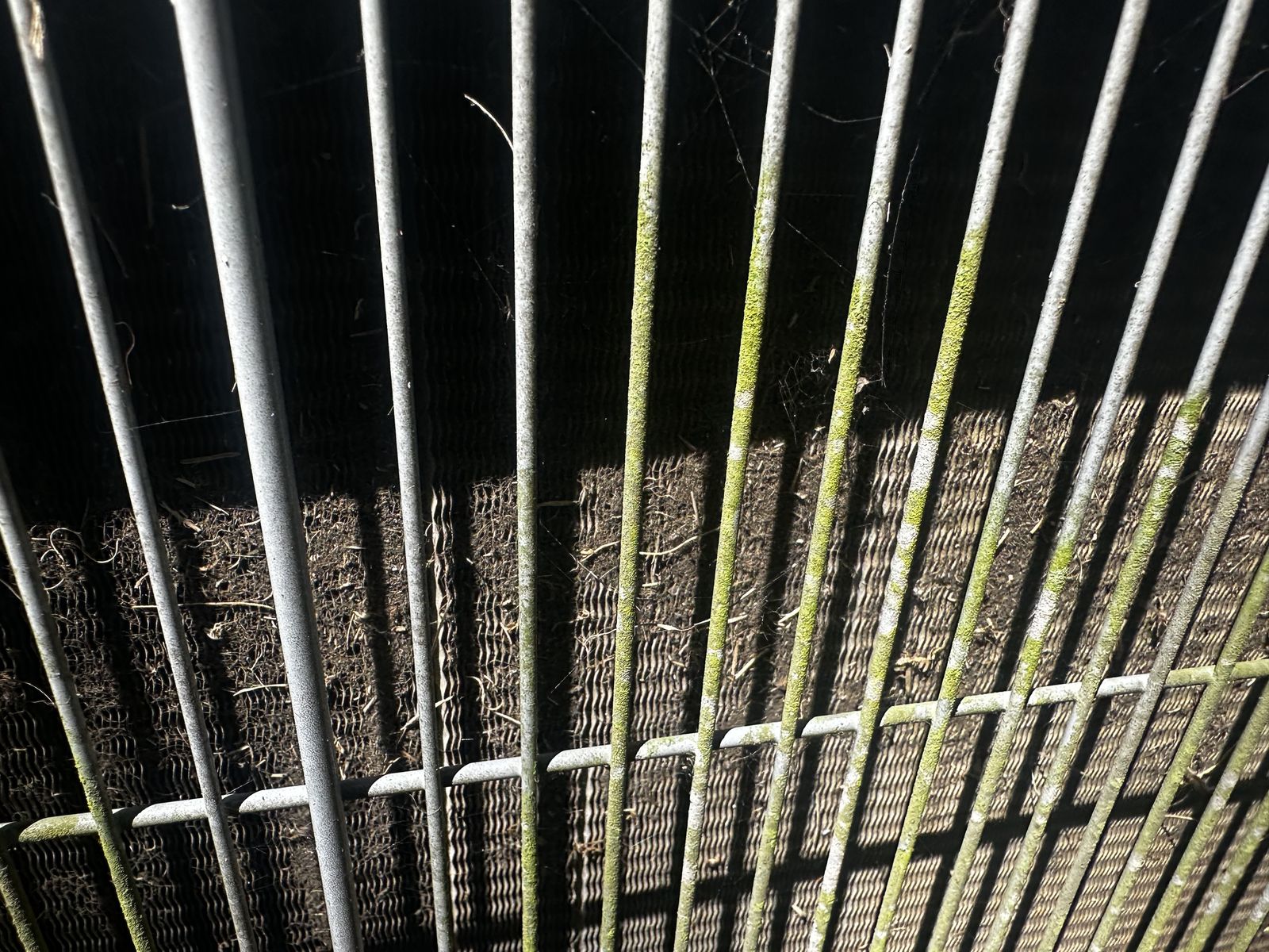 A dirty, debris-clogged AC condenser coil before professional cleaning